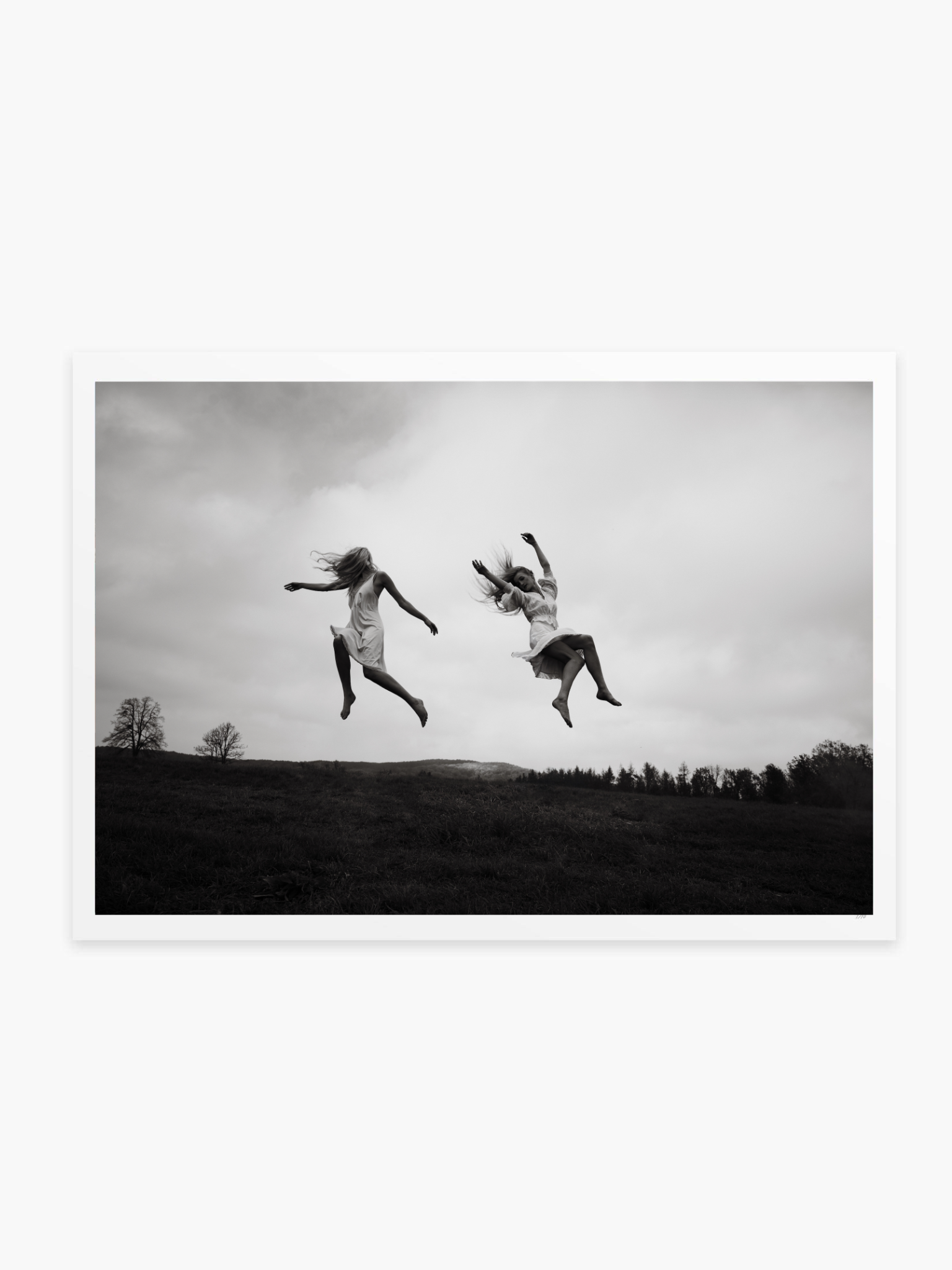 Two people jumping in the air with a landscape background