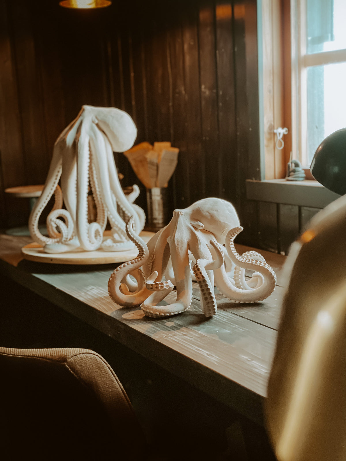 Two white ceramic octopus sculptures by Mia Alajasko on a wooden table